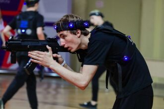 Молодой боец LASERWAR прицеливается из-за укрытия.